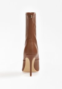 Bottes mi-mollet à talon haut en cuir marron avec un design épuré, bout pointu et fermeture éclair à l'arrière. Texture lisse avec un talon aiguille élancé.