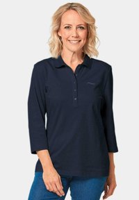 Dunkelblaues Langarm-Polohemd mit Knopfleiste und einem dezenten Logo auf der Brust, aus einem weichen, strukturierten Stoff gefertigt.