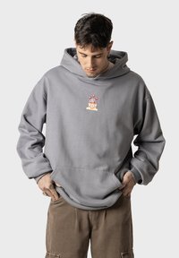 Sudadera con capucha gris y bolsillo frontal, con un diseño gráfico colorido en el pecho. Tejido suave con un ajuste relajado.