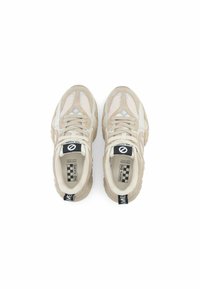 Beige sneakers met mesh zijkanten, gewatteerde tong en een gestructureerde zool. Beschikt over een zwarte hielband met "NO NAME" branding en een geruit patroon op de binnenzool.