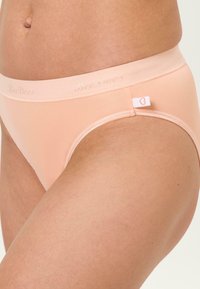 Peach-colored women's underwear with a elastic waistband featuring the brand name "BeeDees" and a small heart tag on the side. Smooth texture.