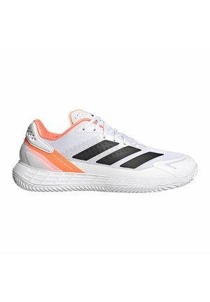 Scarpa sportiva bianca con strisce nere, dettagli arancioni, suola ammortizzata e testo "Defiant Speed" sul lato.