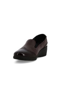 Scarpa slip-on in pelle marrone scuro con dettagli brogue, pannelli laterali elastici neri e suola a zeppa nera.