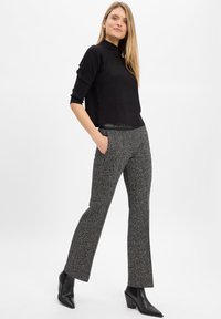 Zwarte geribde lange mouwen top gecombineerd met grijze gestreepte flared broek en spitse zwarte hoge hakken. Eenvoudig ontwerp, gestructureerde stof.