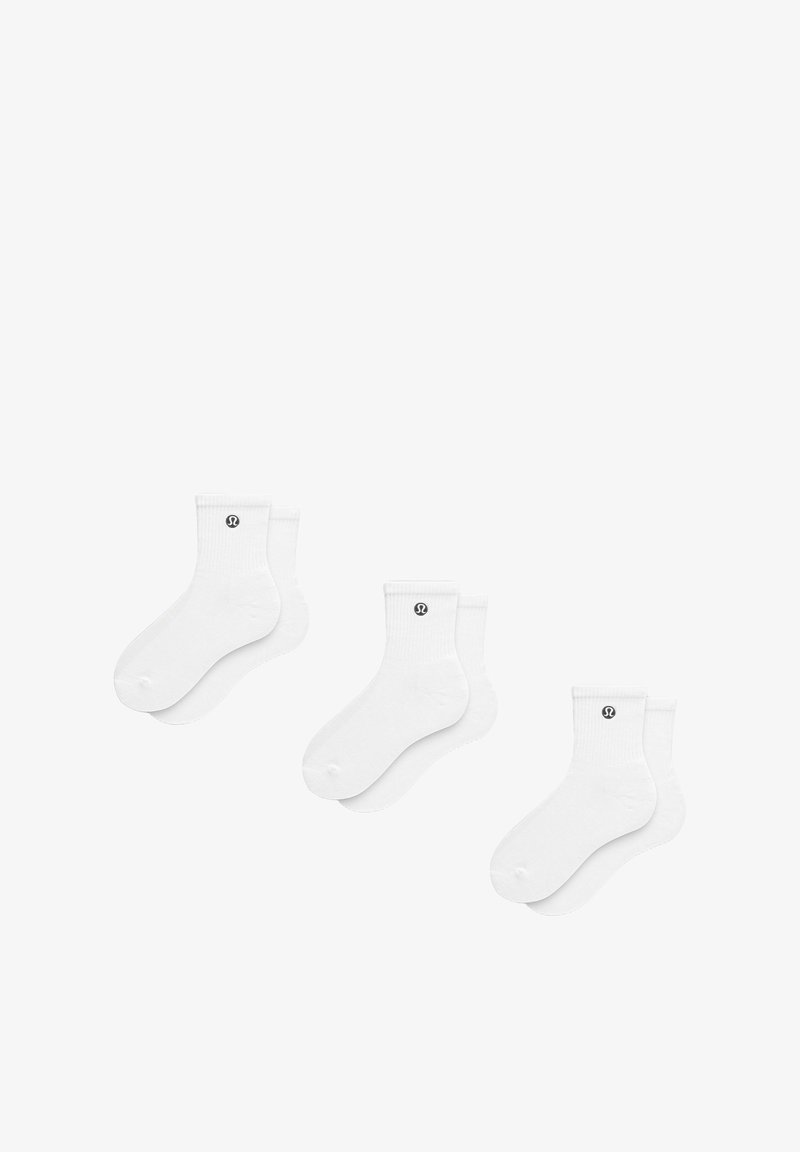 Weiße Socken mit Rippstruktur am oberen Rand, ausgestattet mit einem kleinen schwarzen Logo. Weicher Stoff, ohne Muster, designed für Komfort und den täglichen Gebrauch.