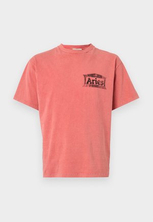 T-shirt corail à manches courtes avec un col rond et une impression graphique noire portant le mot "Aries" sur la poitrine gauche. Tissu en coton doux, coupe décontractée.