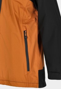 Short jacket featuring an orange body and black sleeves. Side zip pocket in black, with smooth, water-resistant fabric and a matte finish.