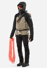 L'équipement d'escalade comprend une veste imperméable noire et beige, un pantalon noir, des gants et une corde d'escalade orange, avec des lunettes de soleil réfléchissantes.