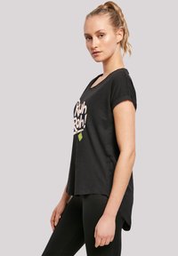 Black t-shirt with a scoop neck, short rolled sleeves, and graphic print reading "Ruh Roh!" in pink, made from soft fabric with a relaxed fit.