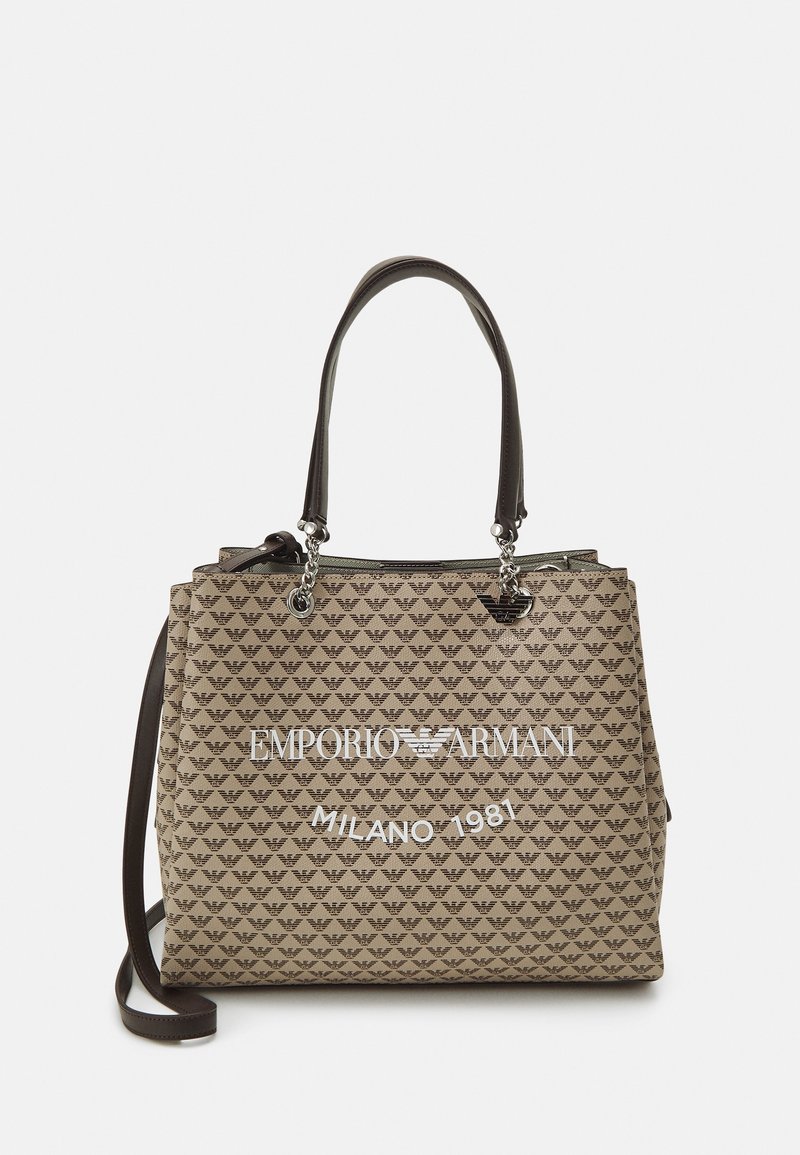 Bolso tote beige con patrón repetido de logotipo de águila de Emporio Armani, asas negras con cadenas plateadas y texto blanco "EMPORIO ARMANI MILANO 1981" en la parte frontal.
