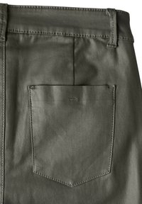 Gröna tygbyxor har en bakficka med en sydd kant och en subtil logotyp, vilket visar på en slät textur och en strukturerad design.