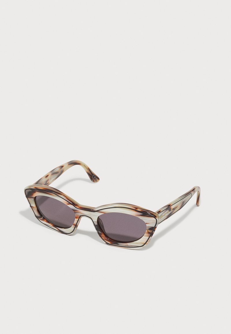 Lunettes de soleil au motif écaille de tortue avec des verres gris, forme de monture angulaire et épaisses branches transparentes avec des accents marron subtils.