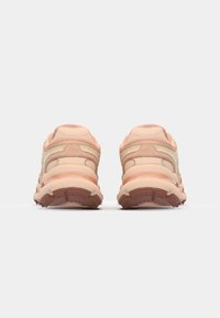 Light beige athletic shoes with textured mesh and synthetic overlays, featuring a padded collar and rubber outsole with traction details.