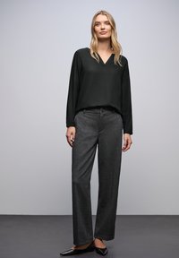 Blusa nera con scollo a V abbinata a pantaloni grigi a gamba larga. Tessuto texturizzato con vestibilità ampia. Ballerine nere a punta completano l'outfit.