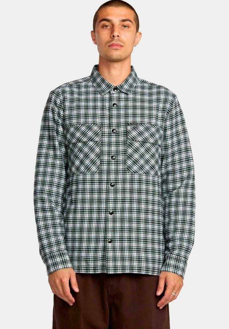 Camisa de cuadros de manga larga en verde y blanco, con dos bolsillos en el pecho y botones negros. Tela de algodón con un acabado texturado.