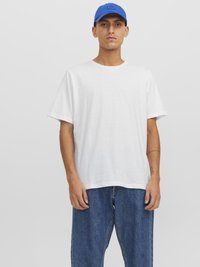 T-shirt en coton blanc avec un col rond et des manches courtes, associé à un jean en denim bleu et une casquette bleue. Design minimaliste dans l'ensemble.