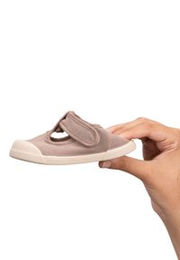 Zapato de tela color marrón claro con una tira de velcro y un corte circular. Suela de goma blanca con rayas horizontales. Pequeño y ligero.
