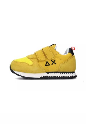 Sneaker giallo per bambino con materiali in suede e rete, presenta due cinturini in Velcro, suola nera a zigzag e linguetta rossa sul tallone.