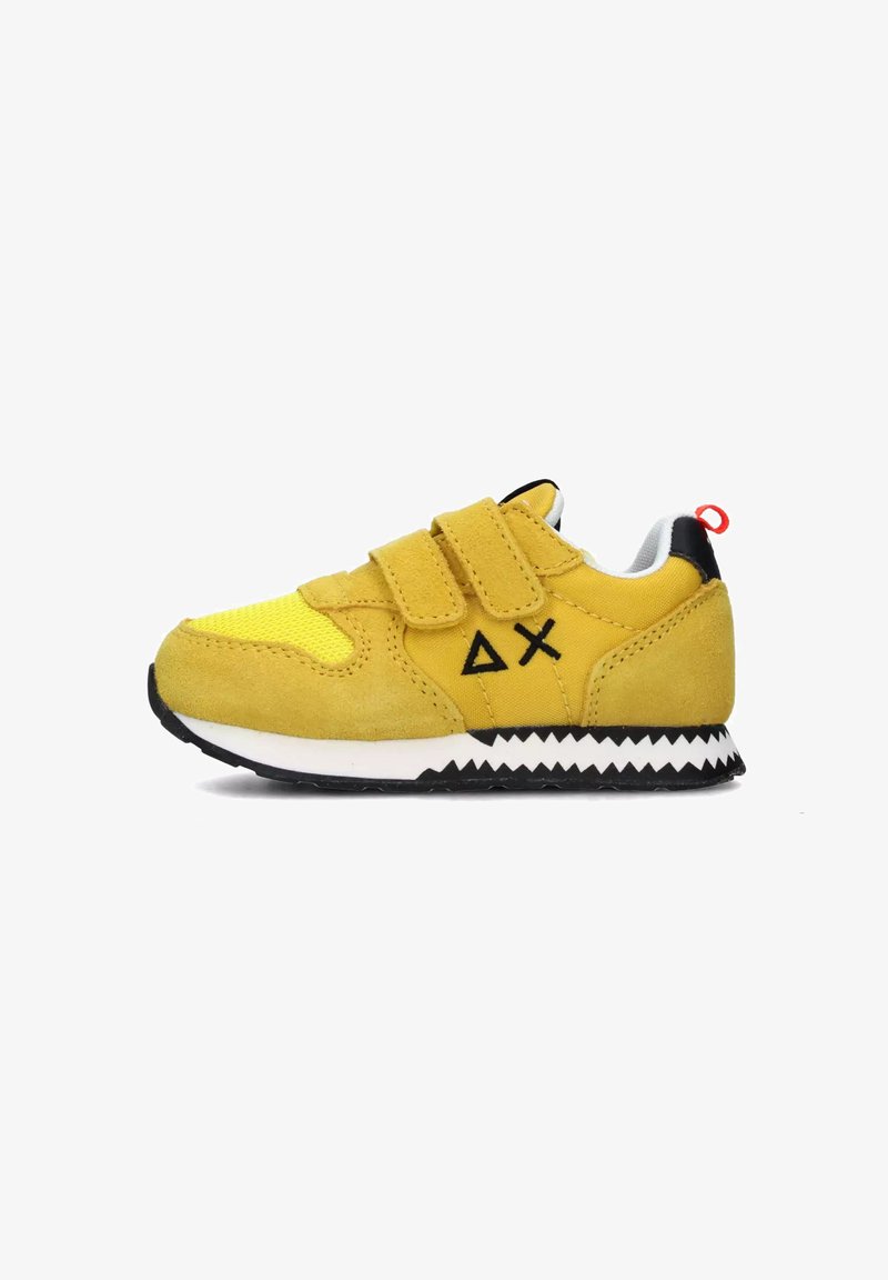 Sneaker giallo per bambino con materiali in suede e rete, presenta due cinturini in Velcro, suola nera a zigzag e linguetta rossa sul tallone.