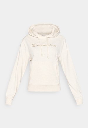 Vaaleabeige huppari kengurutaskulla, nyörisäädettävällä hupulla ja rintakehällä kultaisella kirjotulla ”Champion”-logolla. Pehmeä kangaspinta.