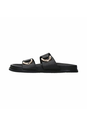 Black leather slide sandals with two straps featuring gold hardware accents, flat sole, textured outsole, and minimalist design.