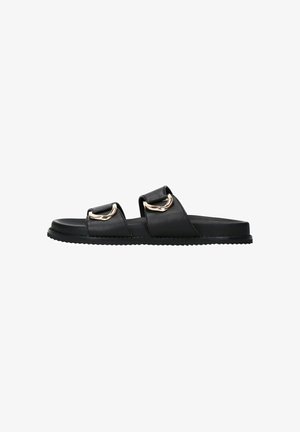 Sandales à glissière en cuir noir avec deux lanières dotées de accents en métal doré, semelle plate, semelle texturée et design minimaliste.