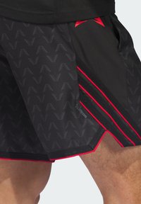 Μαύρο αθλητικό σόρτς με υφή σε σχέδιο «βελονιά ψαροκόκαλο», κόκκινες λεπτομέρειες, πλαϊνές ρίγες και διακοσμητικά από δίχτυ. Διαθέτει ετικέτα Climacool για καλύτερη διαπνοή.