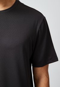 Czarny T-shirt z krótkim rękawem wykonany z teksturowanej tkaniny, z okrągłym dekoltem i prostym wzorem, idealny na codzienne noszenie.