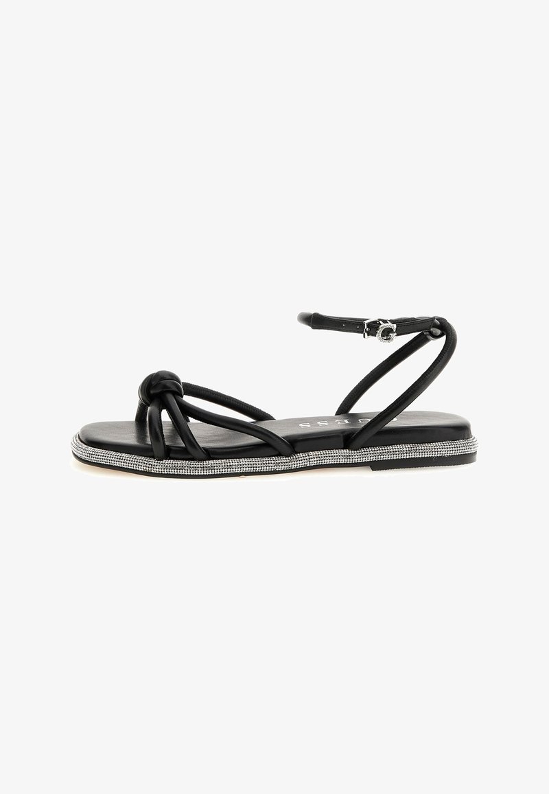 Mustad mustad sandaalid, millel on sõlmedega rihmad, rhinestone-idega kaunistatud tallad ja peen pahkluu rihm kindla istumise tagamiseks.