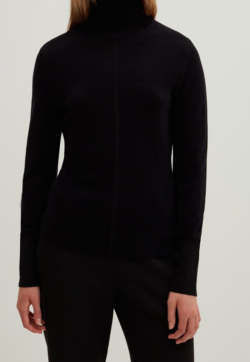 Mustakotoinen poolopaita pehmeästä materiaalista, jossa on pitkät hihat, kapea istuvuus ja sauma etuosassa.