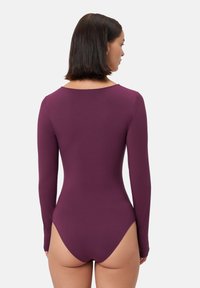 Body a maniche lunghe in un profondo viola, tessuto morbido, scollo a cuore sul retro, silhouette aderente, aperture per le gambe a bassa scollatura, design senza cuciture.