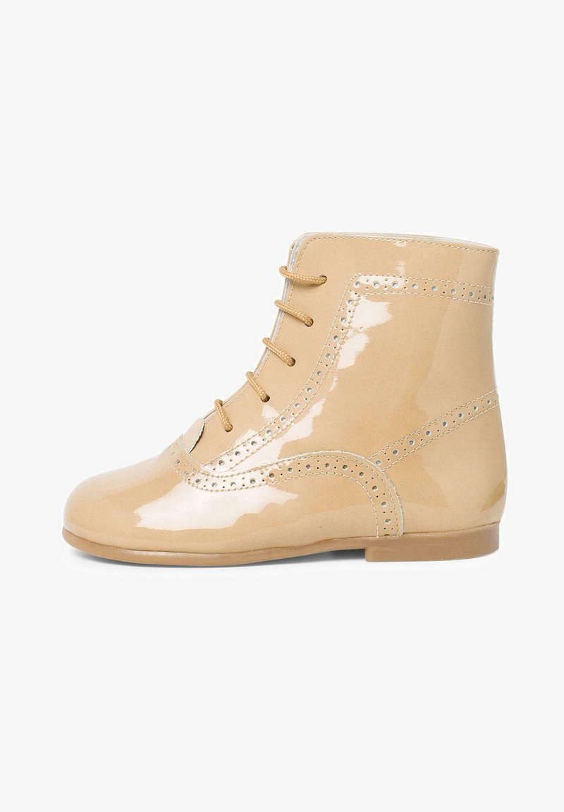 Beige patenten leren enkellaarsjes met ronde neus, decoratieve perforaties langs de naden en beige veters. Platte zool, gladde glanzende afwerking.