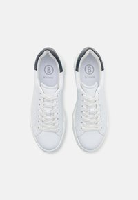 Hvite sneakers med en glatt lærflate, rund tå og snøring. Hælen har en marineblå aksent og en logo på innersålen.