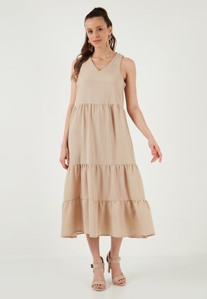 Beige, sleeveless maxi dress with a V-neck and tiered ruffle hem. Made from a textured fabric, it has a relaxed fit and falls to mid-calf.