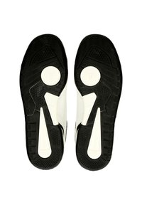 Suole delle scarpe in gomma nera con un logo circolare bianco. Motivo di presa testurizzato con accenti esagonali e vari design del battistrada per migliorare la trazione.