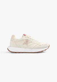 Sneaker in tela beige con suola intermedia bianca, suola esterna in gomma marrone e lacci rosa a contrasto. Presenta un logo a forma di teschio e dettagli di cucitura visibili.
