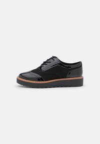 Scarpe in pelle verniciata nera e suede, con lace-up e un design texturizzato, cuciture a contrasto color beige e una suola spessa nera.