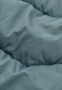Gequiltede dekbedovertrek in een zachte blauwe kleur, met een gladde, matte textuur, zichtbare stiksels en gelijkmatig verdeelde vulling.