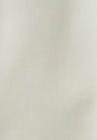 Texture de tissu beige clair uni avec un motif finement tissé et de légères ombres.