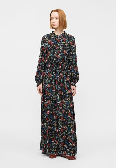 Μακριά φόρεμα σε μαύρο ύφασμα διακοσμημένο με πολύχρωμα λουλουδένια σχέδια. Διαθέτει μακριά μανίκια, γιακά με κουμπιά και ελαστική μέση.