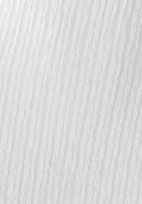 Tissu blanc texturé avec des lignes verticales ondulées, créant un effet de vagues. Léger et transparent avec une finition douce.