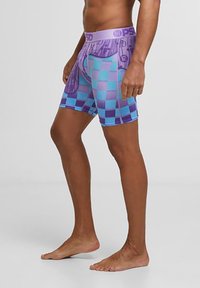 Lilla og turkise rutete herrebokser laget av elastisk stoff, med en bred lilla midjebånd som har logo-detalj.