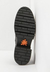 Suela de goma negra con patrón de textura en el taco, con un corte en forma de estrella naranja. Construcción sólida con una superficie de gran agarre.