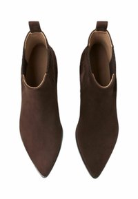 Botas de tobillo de ante marrón con punta afilada, paneles laterales elásticos y una cinta en la parte posterior para ponerlas y quitarlas fácilmente. Textura suave en toda la bota.
