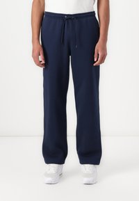 Mörkblå sweatpants i mjukt tyg med elastisk midja, dragsko och sidofickor, avsmalnande vid anklarna.