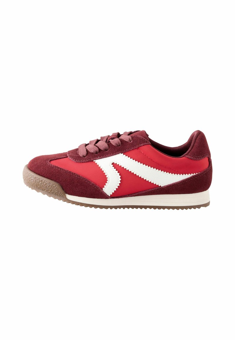 Červená sportovní teniska z semišové a syntetické materiály. Obsahuje bílý cikcakový design, kulatou špičku a drsnou gumovou podrážku. Ploché šňůrky.
