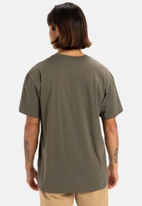 Camiseta de algodón verde oliva con mangas cortas, escote redondo y corte relajado, que presenta una textura suave y un diseño sencillo.