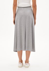 Gray, knee-length, flared skirt made of soft jersey material; features an elastic waistband and a smooth, casual design. Worn with white sneakers.