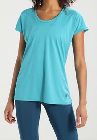 Turkosa tränings t-shirt med korta ärmar och rund halsringning. Tillverkad av ett slätt, lätt tyg och har en liten logotyp vid nederkanten.