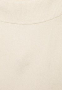 Maglione color crema con scollatura a costine. Superficie morbida e testurizzata senza motivi o accenti visibili.